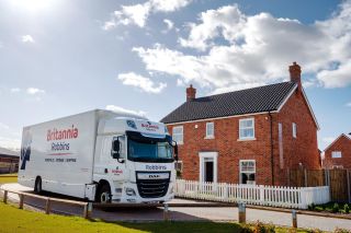 Britannia Robbins branded removal truck parked outside a smart new build home on a sunny day