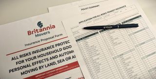 Britannia Movers branded marine insurance paperwork placed on a worktop with a Britannia branded pen.
