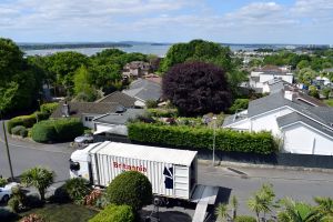 A Britannia branded shipping container is loaded for a move to the Channel Islands with views of the sea in the distance